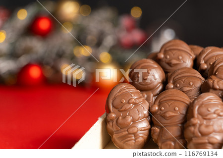 Chocolates in the shape of Christmas figures on the background of a flashing garland 116769134
