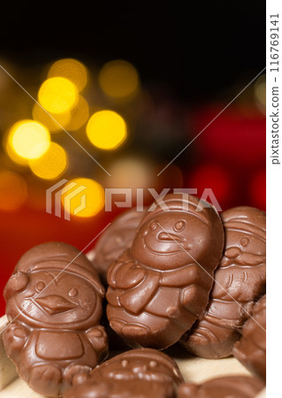 Chocolates in the shape of Christmas figures on the background of a flashing garland 116769141