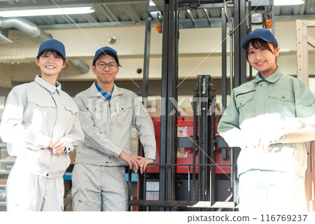 Three workers in work clothes standing in front of a forklift Three workers in work clothes standing in front of a forklift 116769237
