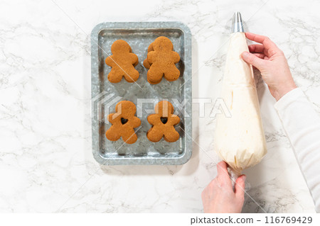 Flat lay. Gingerbread cookies await their second halves on a marble surface, each meticulously piped with buttercream to craft delightful sandwich treats. The precision of the piping adds a festive Flat lay. Gingerbread cookies await their second halves on a marble surface, each meticulously piped with buttercream to craft delightful sandwich treats. The precision of the piping adds a festive 116769429