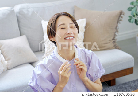 Woman using ice neck ring in living room 116769536