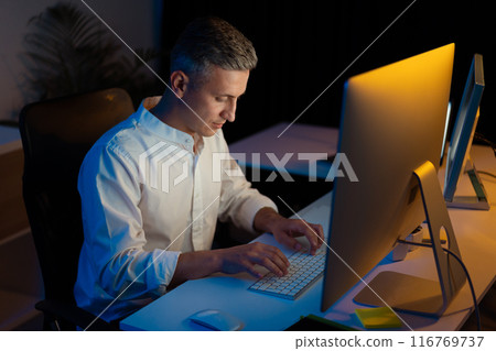 Focused Professional Working Late at Modern Office Desk Focused Professional Working Late at Modern Office Desk 116769737