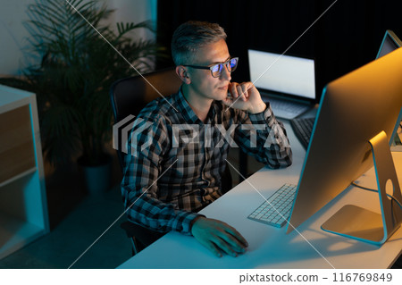 Focused Professional Man Working Late Night on Computer in Office Focused Professional Man Working Late Night on Computer in Office 116769849