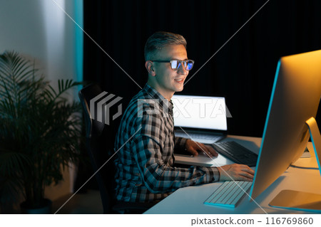 Focused Man Working on Computer Late at Night in Office Focused Man Working on Computer Late at Night in Office 116769860