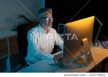 Focused Professional Working Late at Night in Modern Office Focused Professional Working Late at Night in Modern Office 116770003