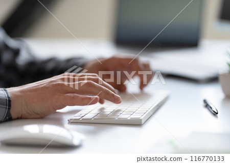 Close-Up of Hands Typing on a Keyboard in Office Setting 116770133
