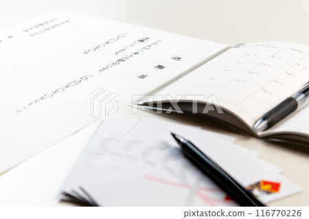 Handwritten resignation letters and a new schedule book, a selection envelope and a brush pen gathered on a white table 116770226