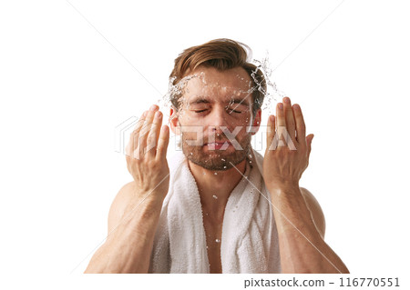 Handsome young man washing face with towel on shirtless body, doing morning facial routine isolated on white background 116770551