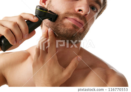 Cropped image of shirtless handsome man using trimmer on beard, isolated on white background. Contemporary male grooming. 116770553