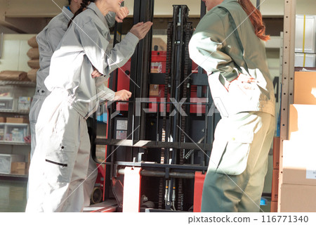 Three male and female workers inspecting a forklift Three male and female workers inspecting a forklift 116771340