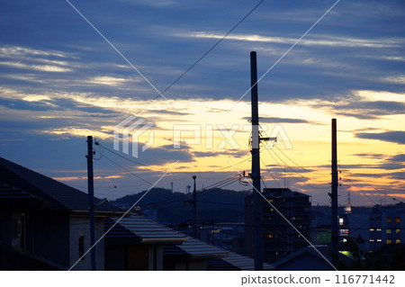 Sunset sky seen from a residential area with utility poles 116771442