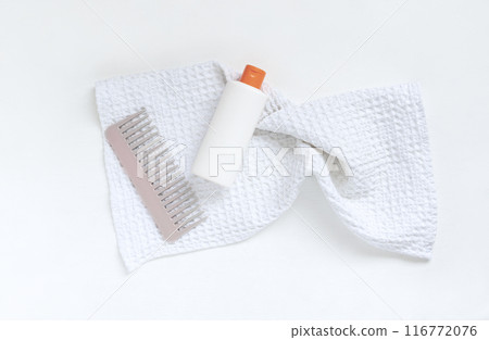 Plastic white shampoo bottle and comb on white textured towel. Idea of image of hair care product. Mockup template for cosmetics. 116772076