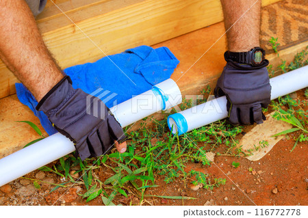 Contractor installing glue on plastic PVC pipes for laying water line Contractor installing glue on plastic PVC pipes for laying water line 116772778