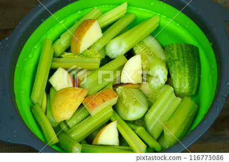 Green bowl filled with chopped celery, cucumber, and apple slices. Green bowl filled with chopped celery, cucumber, and apple slices. 116773086