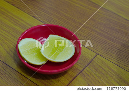 Two halves of a juicy lime rest in a vibrant red bowl. Two halves of a juicy lime rest in a vibrant red bowl. 116773090