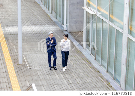 A businessman and an engineer walking down an aisle while talking 116773518