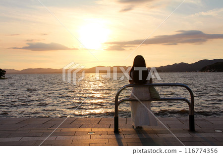 一個女人在湖邊享受夕陽 116774356