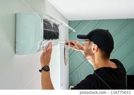Air conditioner maintenance. Male technician repairing cooling system Air conditioner maintenance. Male technician repairing cooling system 116775631