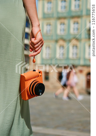 Female tourist captures memories during travel with vintage instant camera 116775658