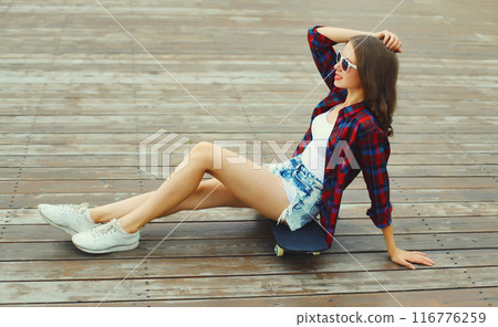 Stylish young woman with skateboard in casual clothes, modern teenage girl posing in the city 116776259