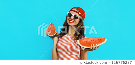 Summer portrait of happy young woman eating fresh slice of watermelon on blue background Summer portrait of happy young woman eating fresh slice of watermelon on blue background 116776287
