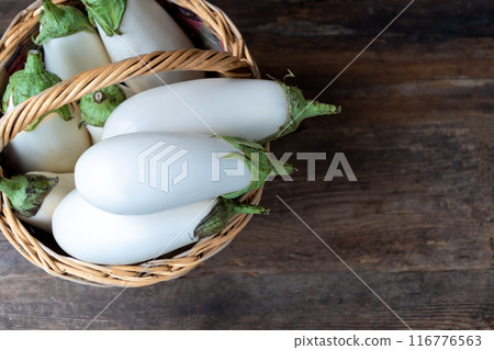Harvest white eggplants on a wooden background with place for text. Eggplant vegetable on the table. Food with copy space Harvest white eggplants on a wooden background with place for text. Eggplant vegetable on the table. Food with copy space 116776563