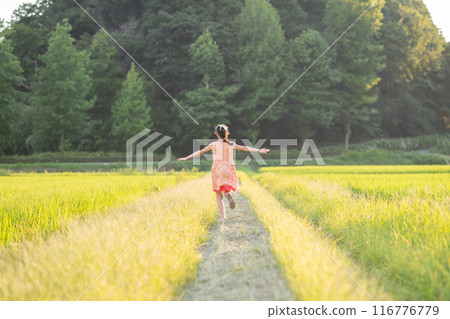 A girl playing on a rice field path at dusk 116776779
