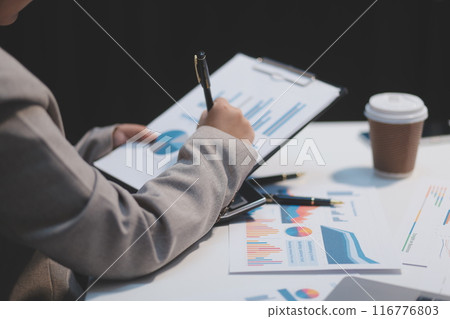 Business woman using calculator and writing make note with calculate. Woman working at office with laptop and documents on his desk 116776803