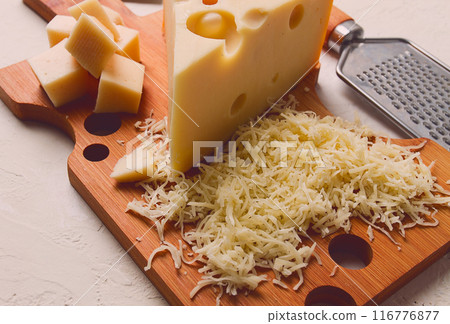 Grated cheese, Maasdam, on a cutting board, grater and cheese knife, close-up, no people, 116776877
