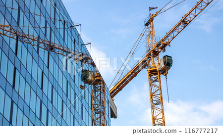 During the day, a crane is seen in front of a building under construction 116777217
