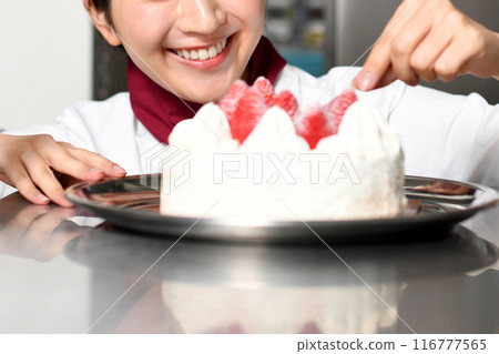 A female pastry chef preparing a whole cake 116777565