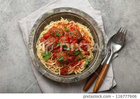 Spaghetti and meatballs with tomato sauce served on rustic plate with cutlery top view, Italian cuisine 116777606