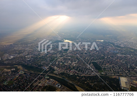 Aerial view from high altitude of distant city covered with puffy cumulus clouds forming before rainstorm in evening. Airplane point of view of cloudy landscape 116777706