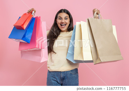 Amazed woman wearing casual T-shirt and jeans showing shopping bags Amazed woman wearing casual T-shirt and jeans showing shopping bags 116777755