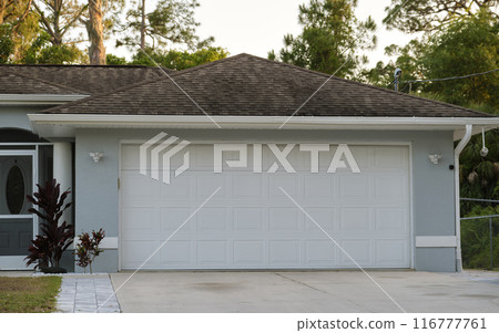 Wide garage double door and concrete driveway of new modern american house Wide garage double door and concrete driveway of new modern american house 116777761