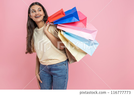 Brunette woman wearing casual T-shirt and jeans holding shopping bags enjoying shopping mall exploration 116777773