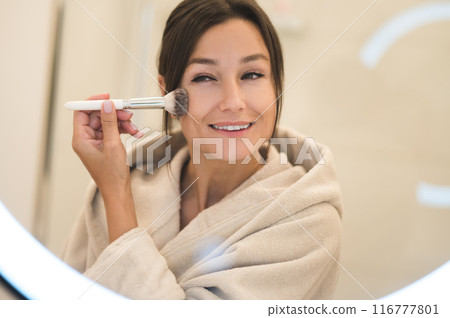 Cute caucasian dark-haired woman at the mirror in the bathroom Cute caucasian dark-haired woman at the mirror in the bathroom 116777801