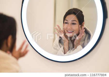 Cute caucasian dark-haired woman at the mirror in the bathroom 116777804