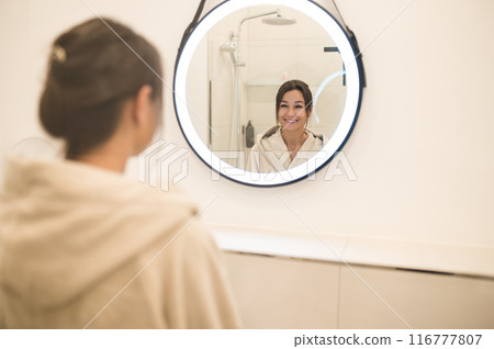 Cute caucasian dark-haired woman at the mirror in the bathroom 116777807