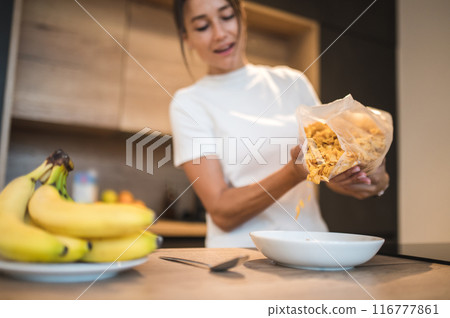 Young dark-haired woman preparing breakfast in the kitchen Young dark-haired woman preparing breakfast in the kitchen 116777861