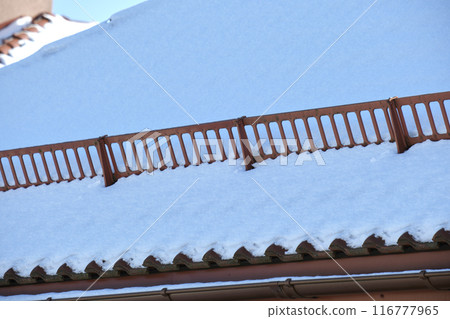 Snow guard for safety in winter on house roof top covered with steel shingles. Tiled covering of building 116777965