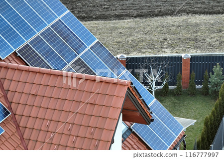 Residential house with rooftop covered with solar photovoltaic panels for producing of clean ecological electrical energy in suburban rural area. Concept of autonomous home Residential house with rooftop covered with solar photovoltaic panels for producing of clean ecological electrical energy in suburban rural area. Concept of autonomous home 116777997