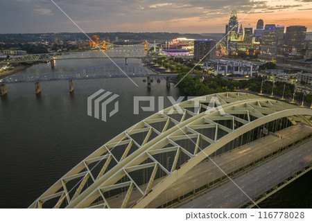 Night urban landscape of downtown district of Cincinnati city in Ohio, USA. Skyline with driving cars on bridge and brightly illuminated high skyscraper buildings in modern American megapolis Night urban landscape of downtown district of Cincinnati city in Ohio, USA. Skyline with driving cars on bridge and brightly illuminated high skyscraper buildings in modern American megapolis 116778028