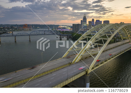 Night urban landscape of downtown district of Cincinnati city in Ohio, USA. Skyline with driving cars on bridge and brightly illuminated high skyscraper buildings in modern American megapolis 116778029