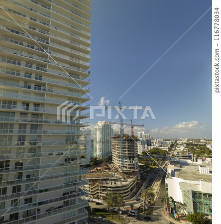 New construction site of developing residense in american urban area. Industrial tower lifting cranes in Miami, Florida. Concept of housing growth in the USA 116778034