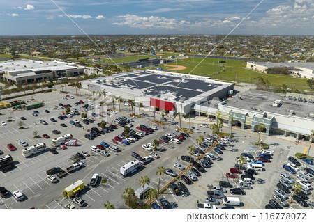 Large parking lot with many parked cars. Big carpark at supercenter shopping mall with lines and markings for vehicle places and directions 116778072