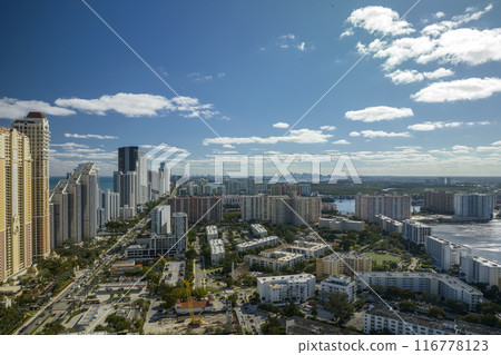 High angle view of Sunny Isles Beach city with expensive highrise hotels and condo buildings on Atlantic ocean shore. American tourism infrastructure in coastal southern Florida 116778123