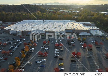 View from above of american grocery store with many parked cars on parking lot with lines and markings for parking places and directions. Place for vehicles in front of a strip mall center View from above of american grocery store with many parked cars on parking lot with lines and markings for parking places and directions. Place for vehicles in front of a strip mall center 116778236