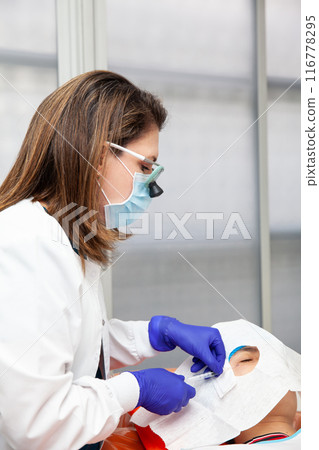 Skin lesion removal procedure. Dermatologist carrying out a removal of benign skin lesion on the face of a young male patient. 116778295