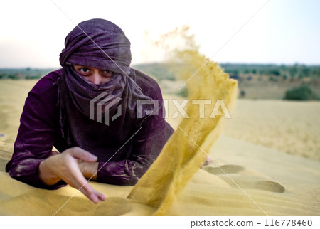 Mature Masculine Spanish model covered with turban playing at desert with sand 116778460